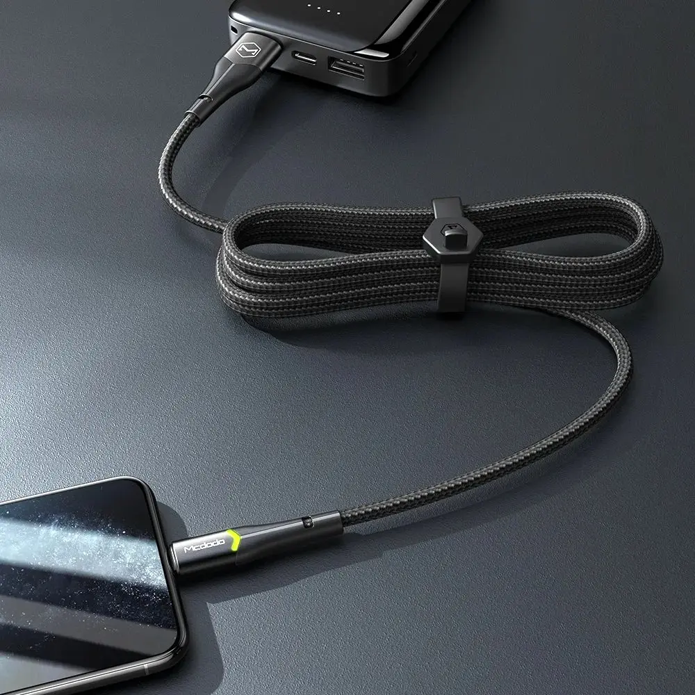 Siyah örgülü bir kablo, telefonla powerbank'ı birbirine bağlar, kablo düzgünce sarılmıştır.
