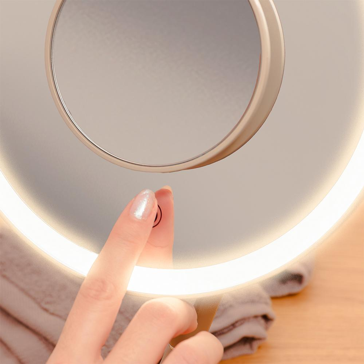 Una mano con esmalte brillante toca un espejo iluminado.