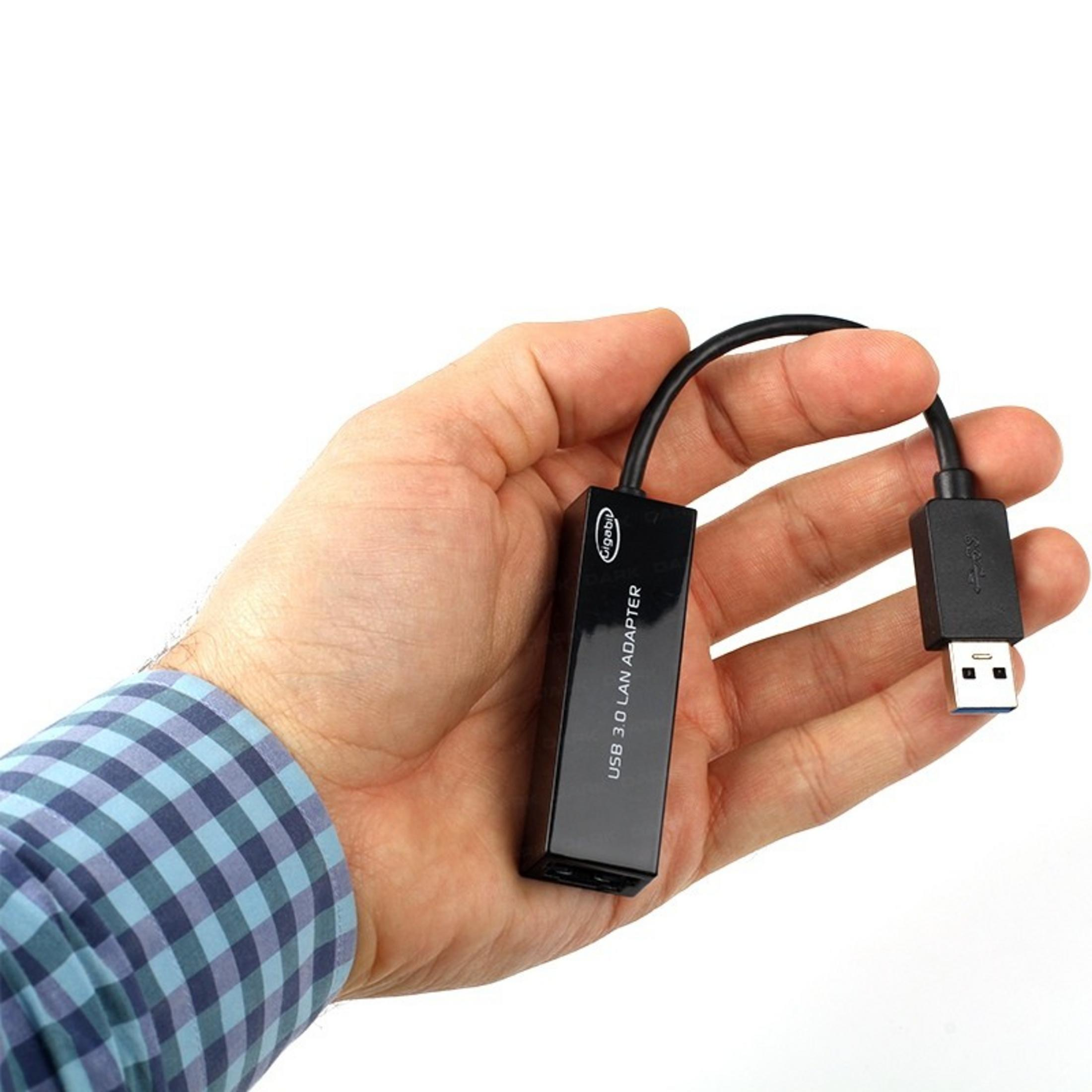 Bir adam kablosu ve fişiyle birlikte siyah bir USB 3.0 LAN adaptörü tutuyor.