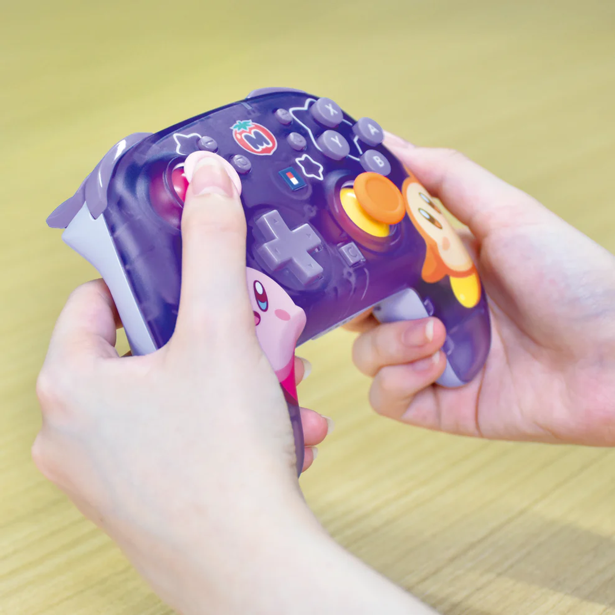 Manos sujetando un mando de Kirby morado.