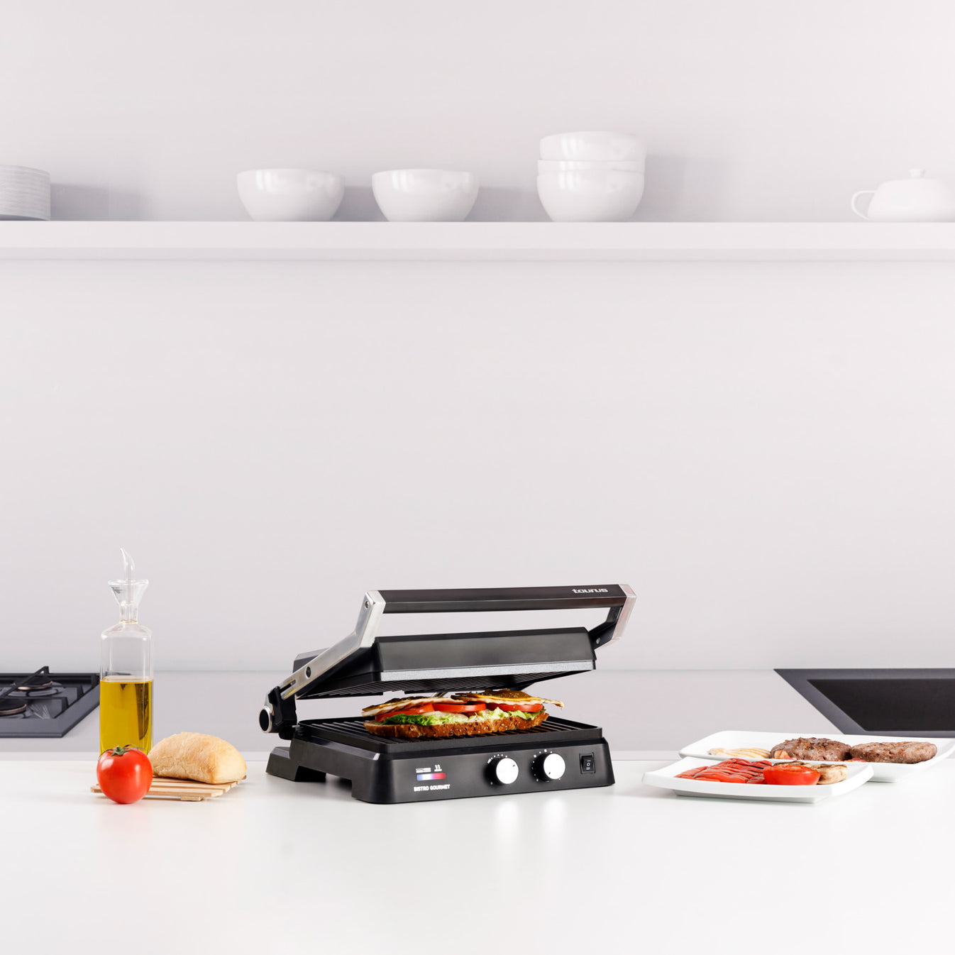 Un sandwich maker con un panino, pane, pomodoro e olio d'oliva.