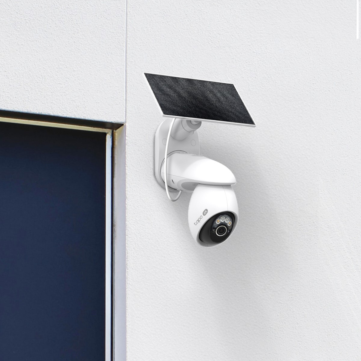 Cámara de seguridad blanca con panel solar montada en pared blanca.