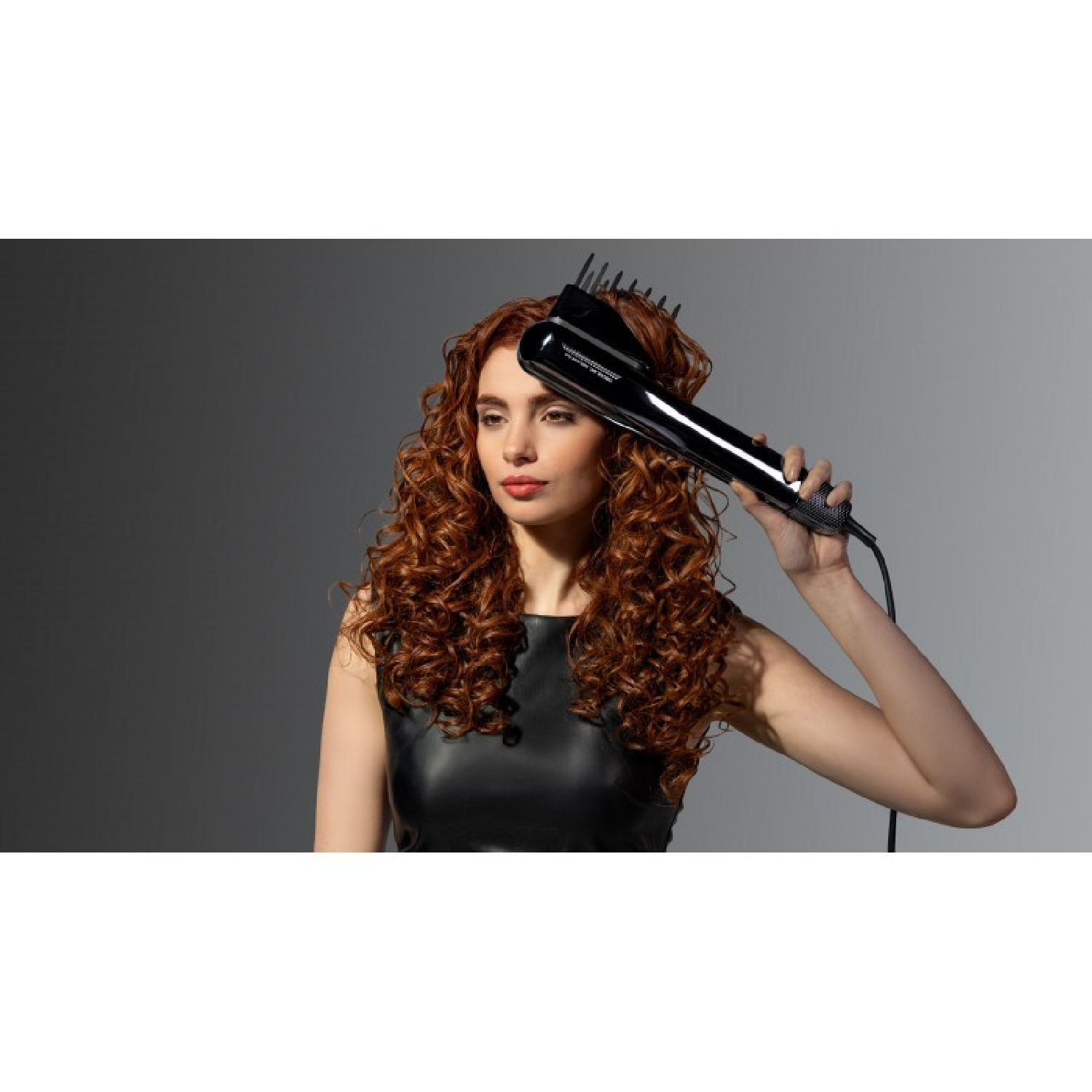 Una donna con capelli rossi ricci usa un arricciacapelli nero.