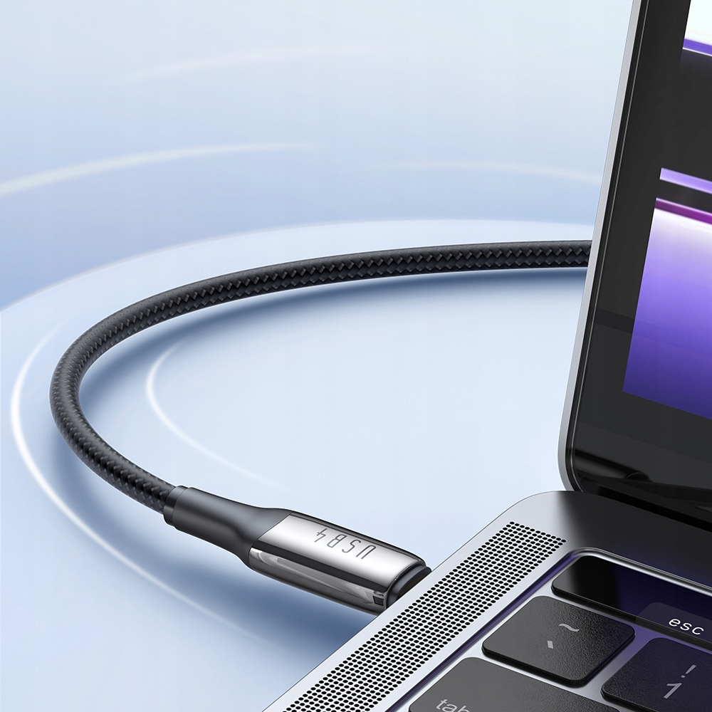 Siyah bir USB-C kablosu, gümüş renkli bir dizüstü bilgisayar klavyesine takılıdır. Kablonun metal konektörü vardır.