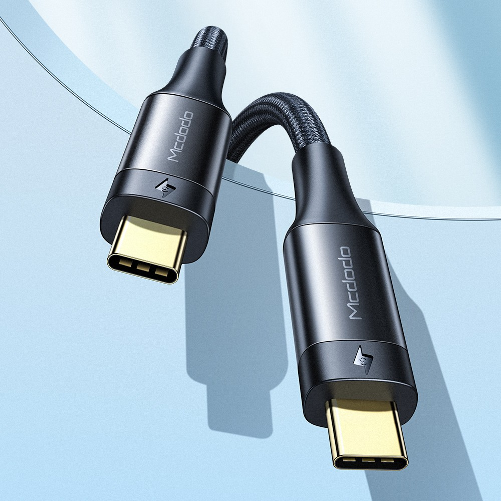 Altın konektörlü iki siyah USB-C kablosu mavi zeminde duruyor.