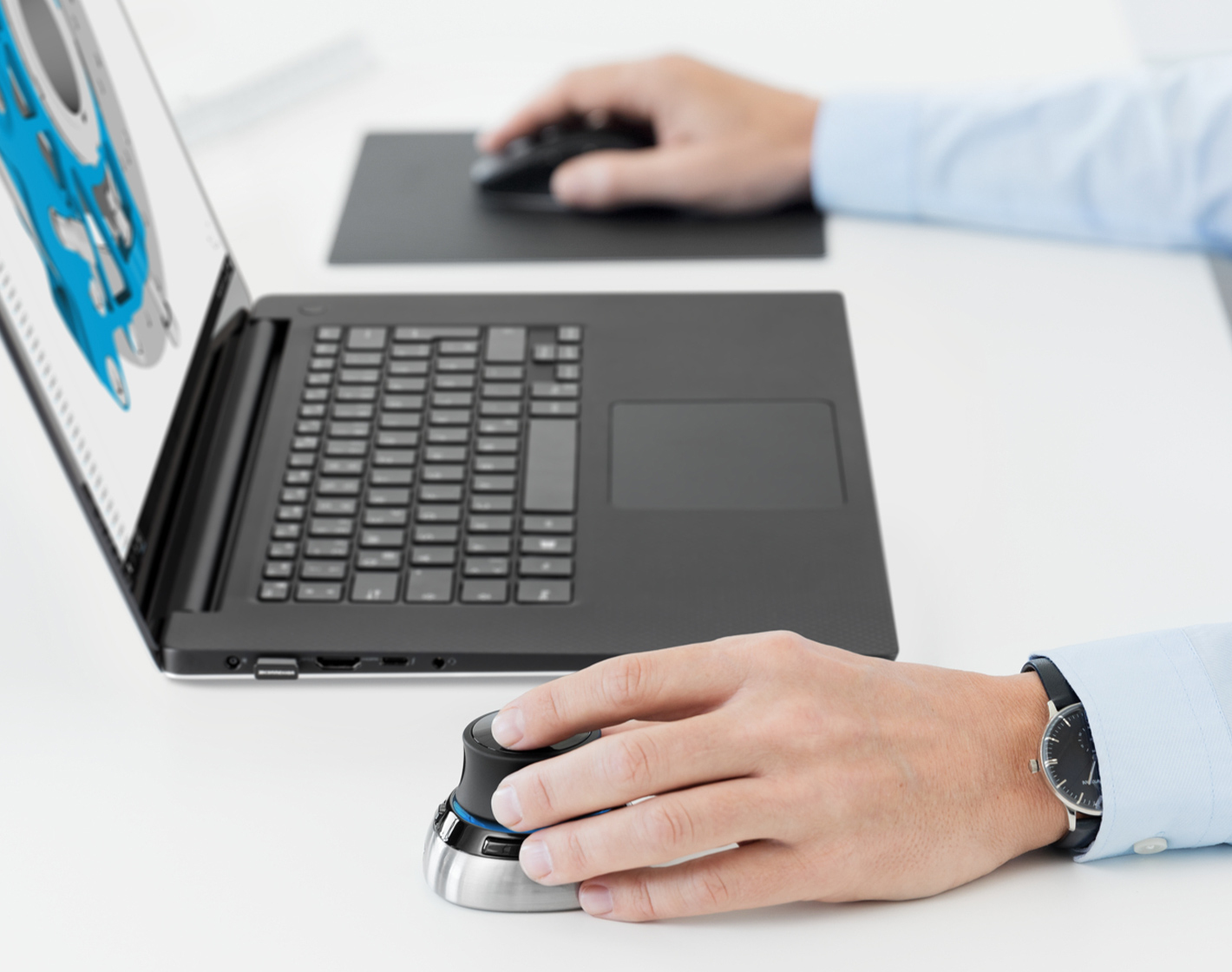 Een man gebruikt een 3D-muis en laptop om een blauw 3D-model te bewerken.