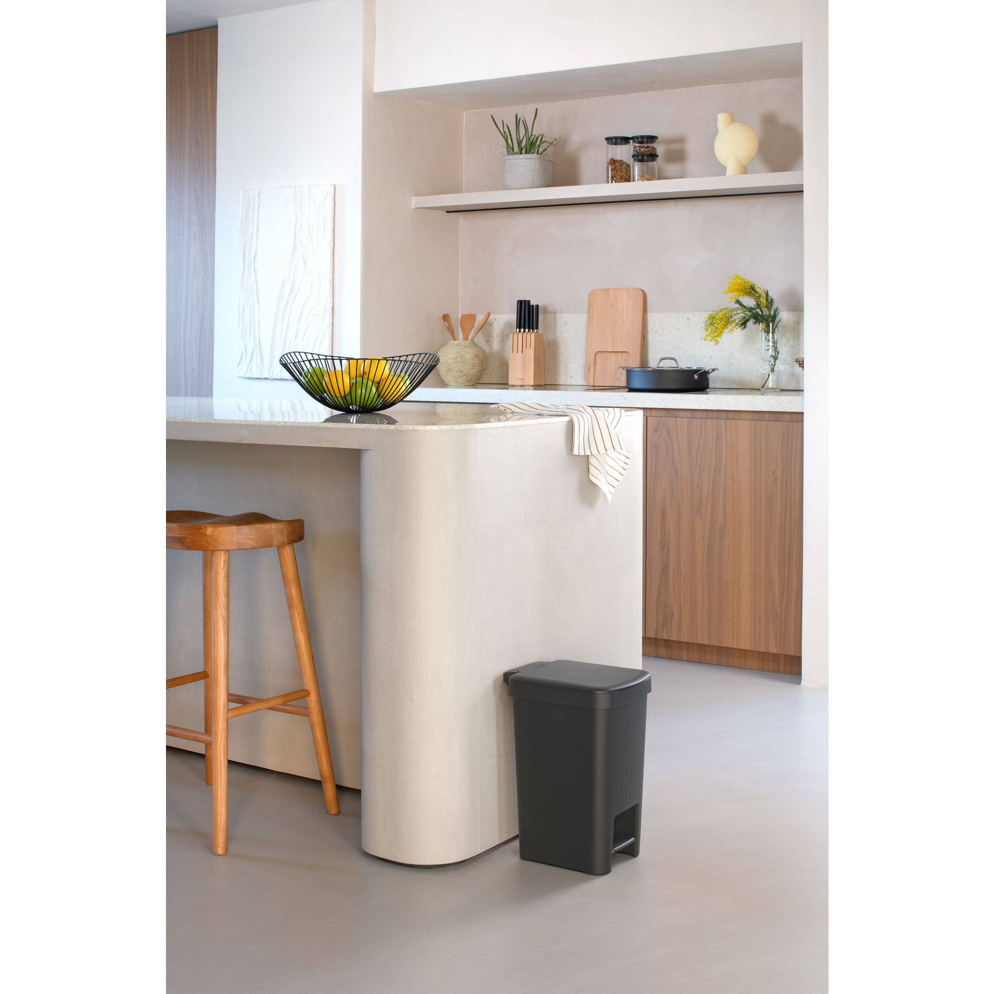 Moderne keuken met aanrecht, kruk, fruitschaal en prullenbak.
