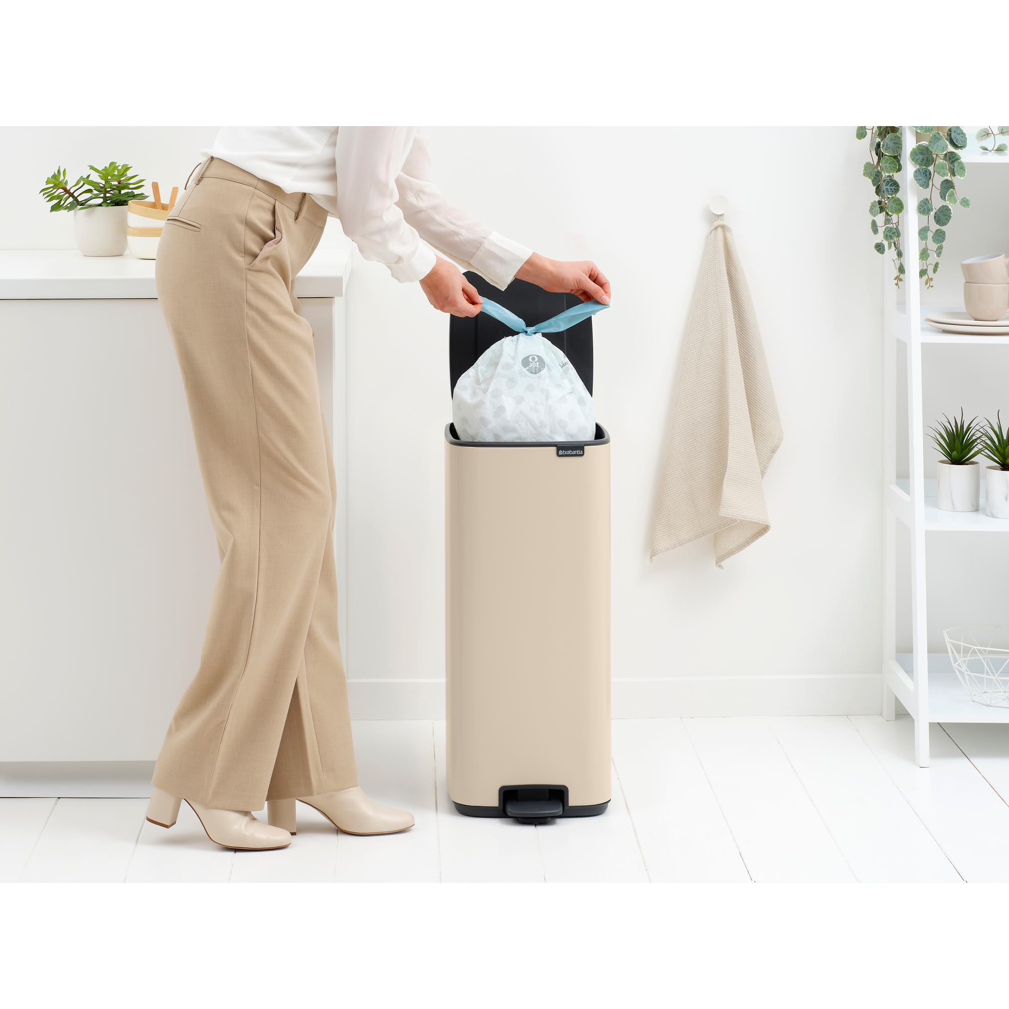 Vrouw strikt vuilniszak in een beige prullenbak.