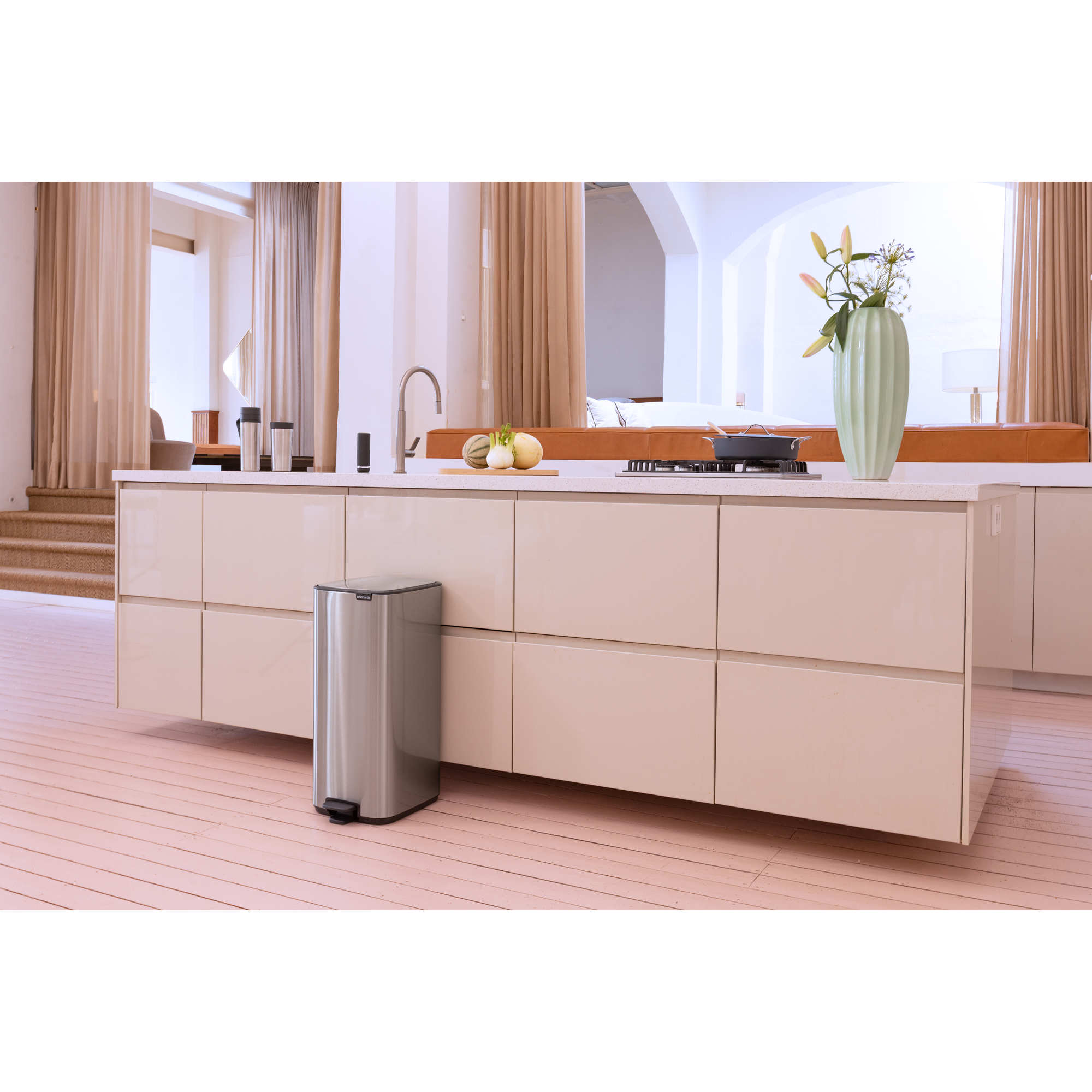 Moderne keuken met eiland, prullenbak, fornuis en bloemen in vaas.