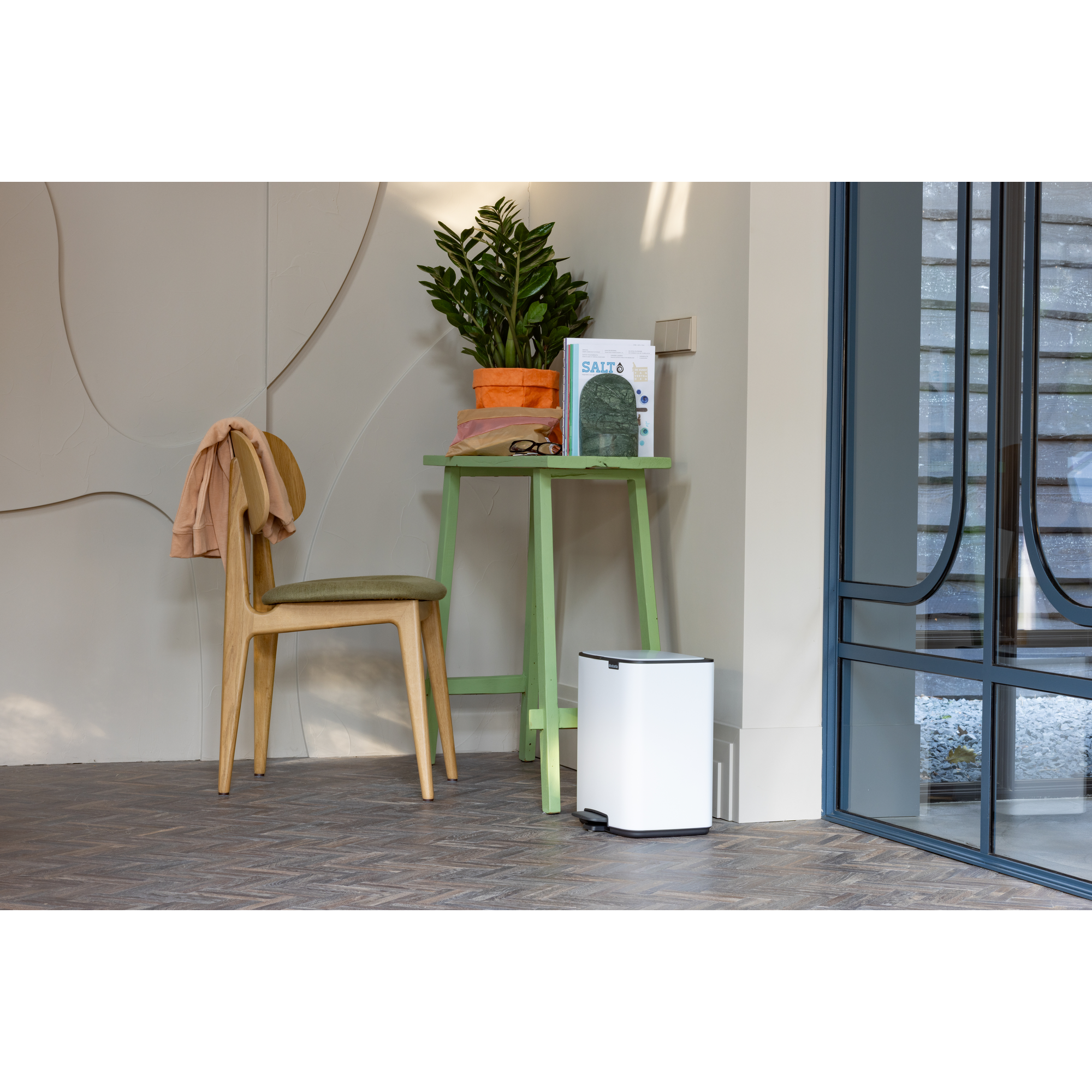 Een houten stoel met groene zitting staat naast een groene tafel met planten.