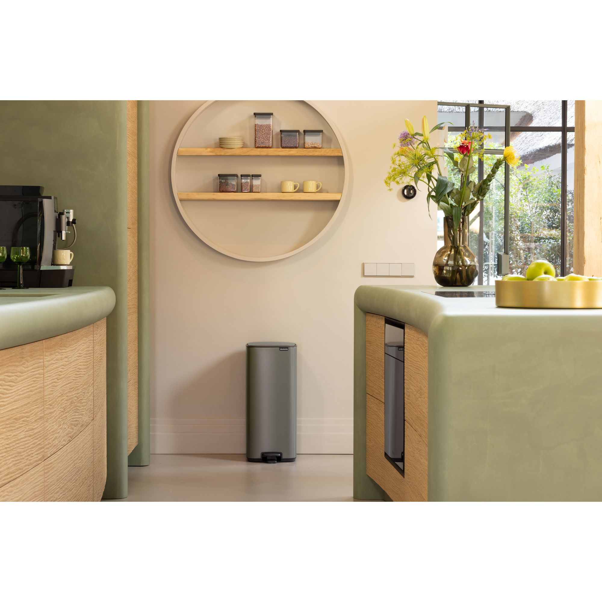Een moderne keuken met groene aanrechtbladen, houten kasten en een rond rek.