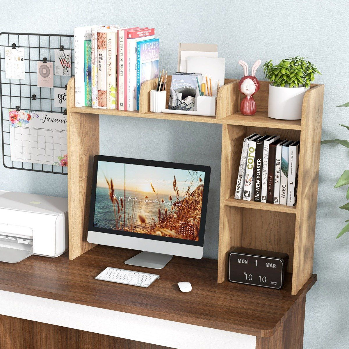 Bureau met computer, printer, boeken, kalender en decoratieve items.