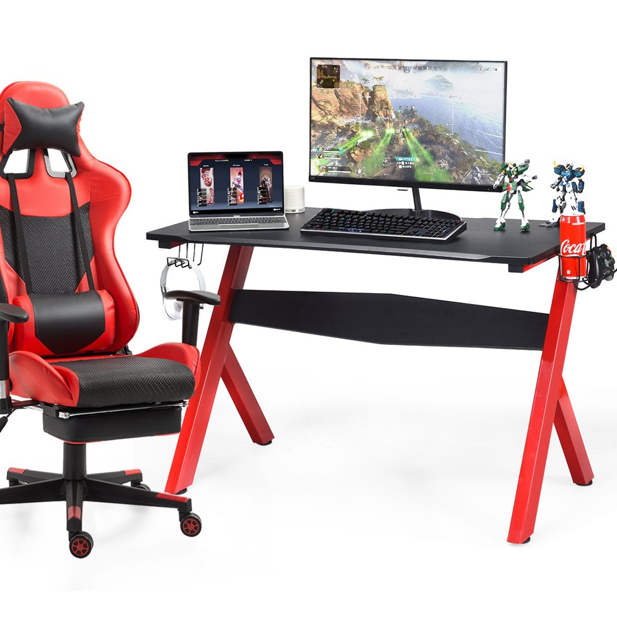 Rode gamestoel en bureau met computer, laptop, toetsenbord, figuren en Coca-Cola blikje.