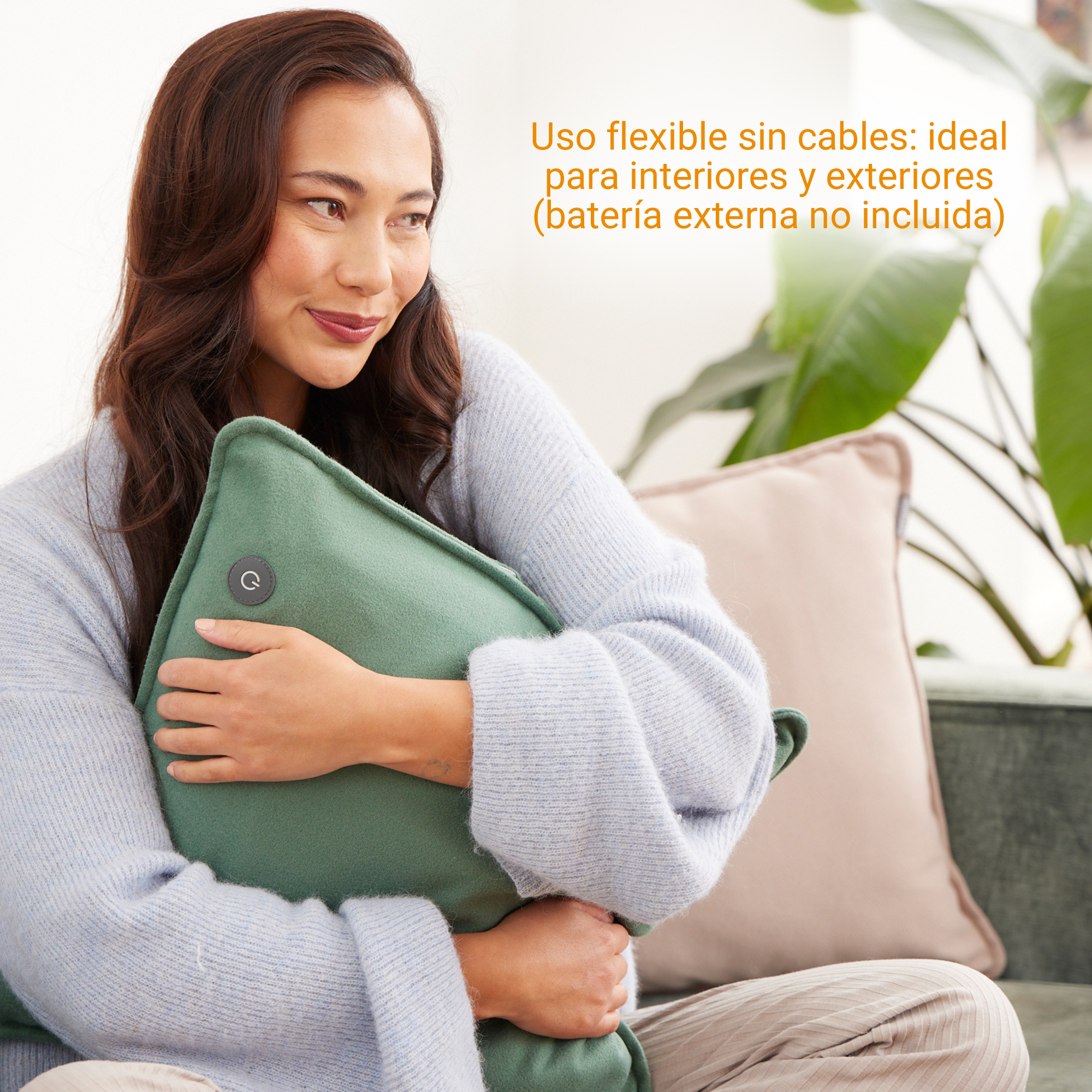 Una mujer sostiene un cojín verde. Lleva un suéter azul.
