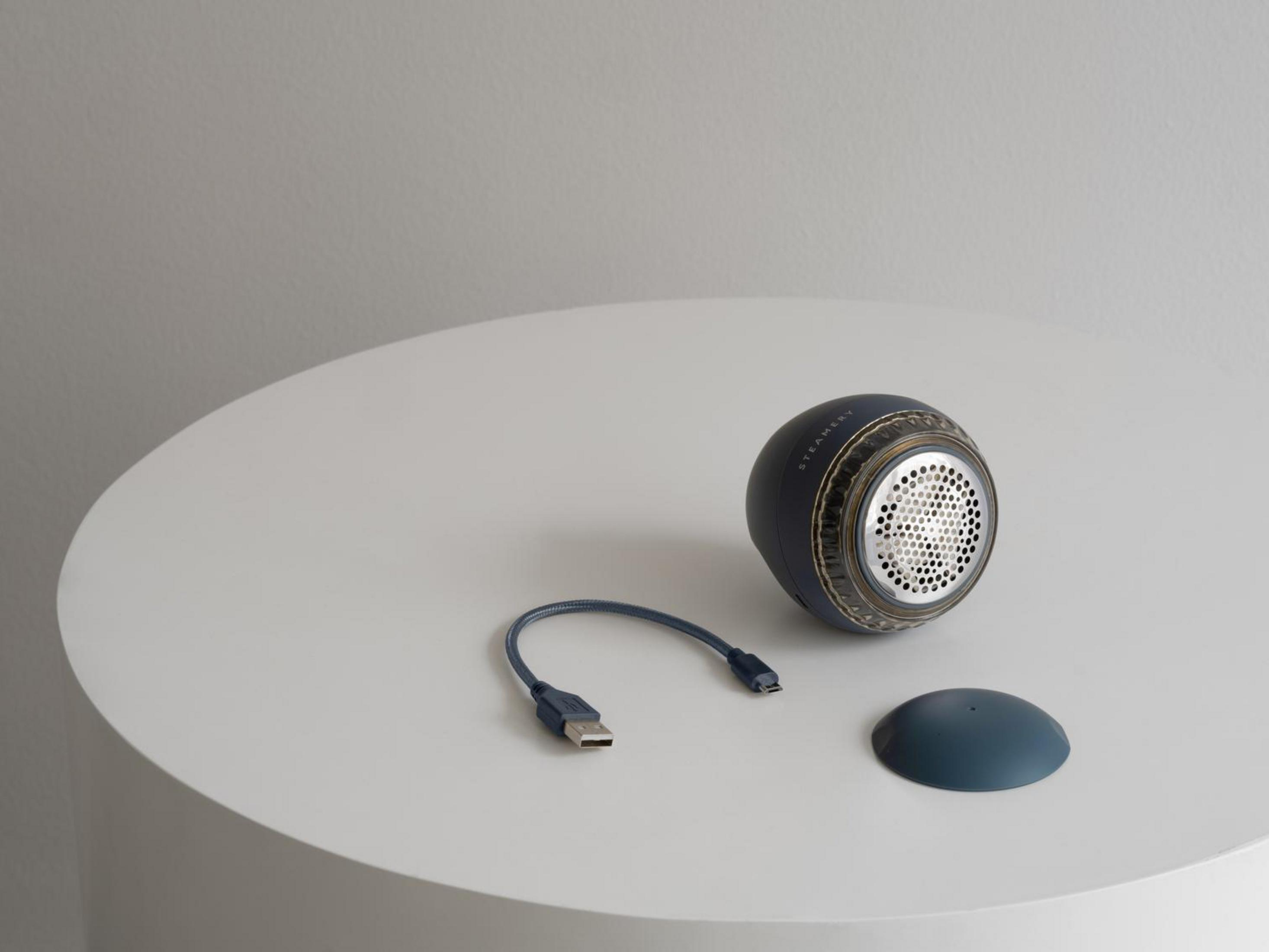 Dunkelblaues Gerät mit USB-Kabel und Kappe auf weißem Tisch.