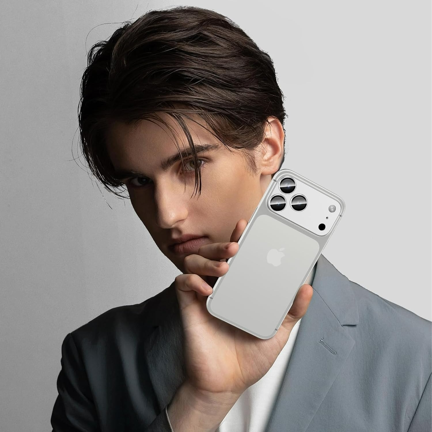 Gri takım elbiseli bir adam, üç kameralı şeffaf bir telefon tutuyor.