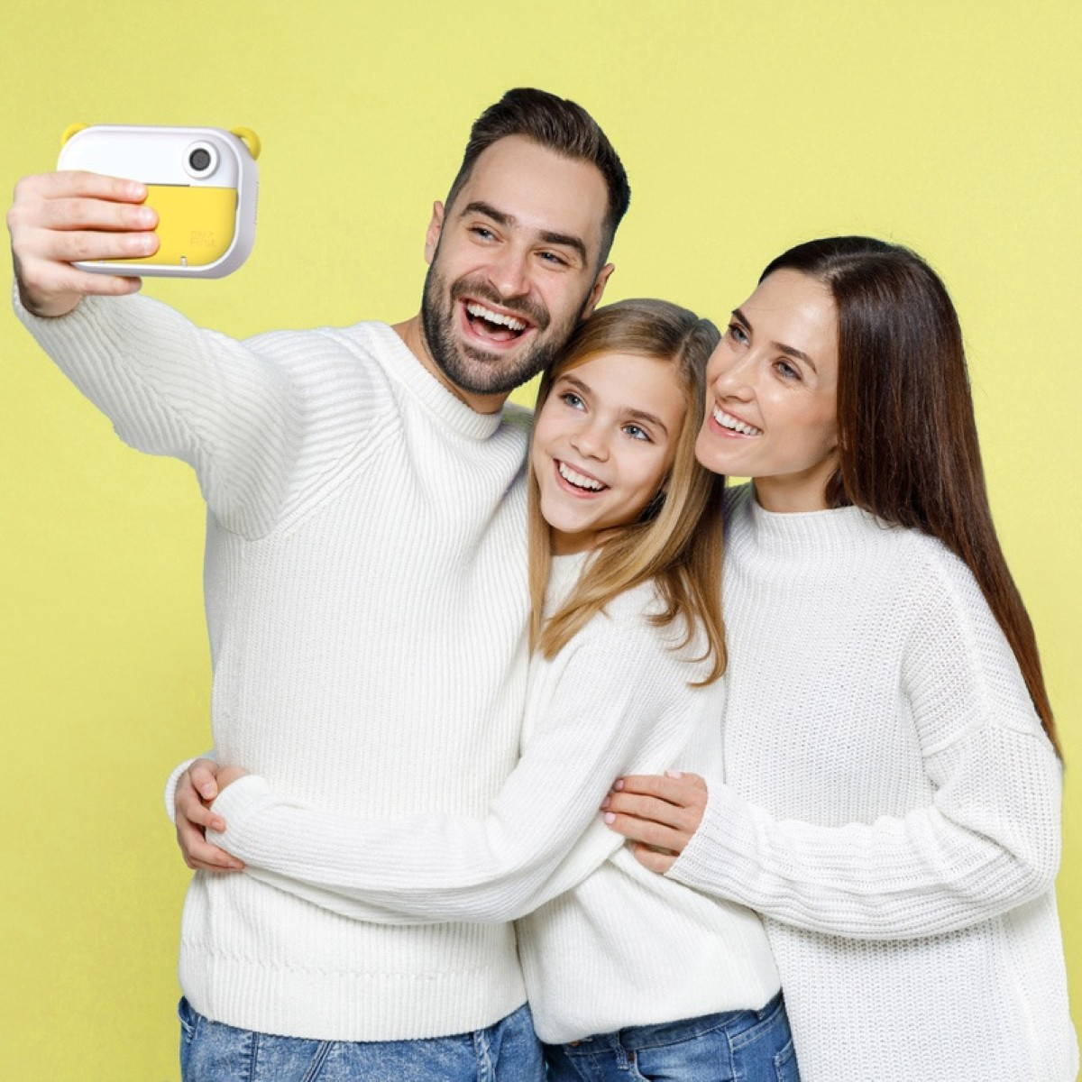 Familie macht Selfie mit gelber Kamera vor gelbem Hintergrund.