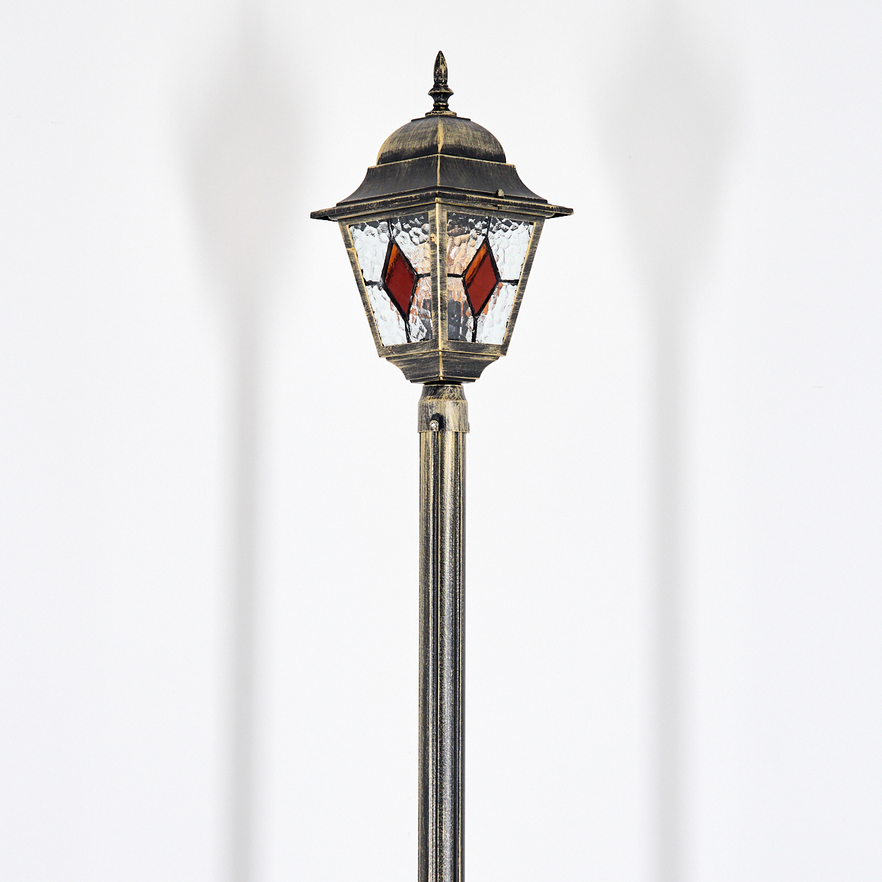 Eine antike Stehlampe mit goldener Fassung und roten Glasdetails.