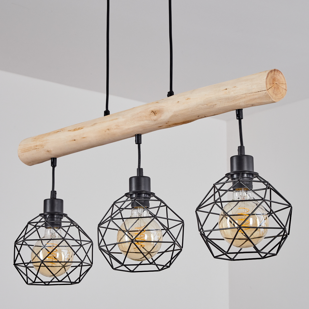 Hängeleuchte mit Holzstamm und drei schwarzen geometrischen Lampenschirmen.