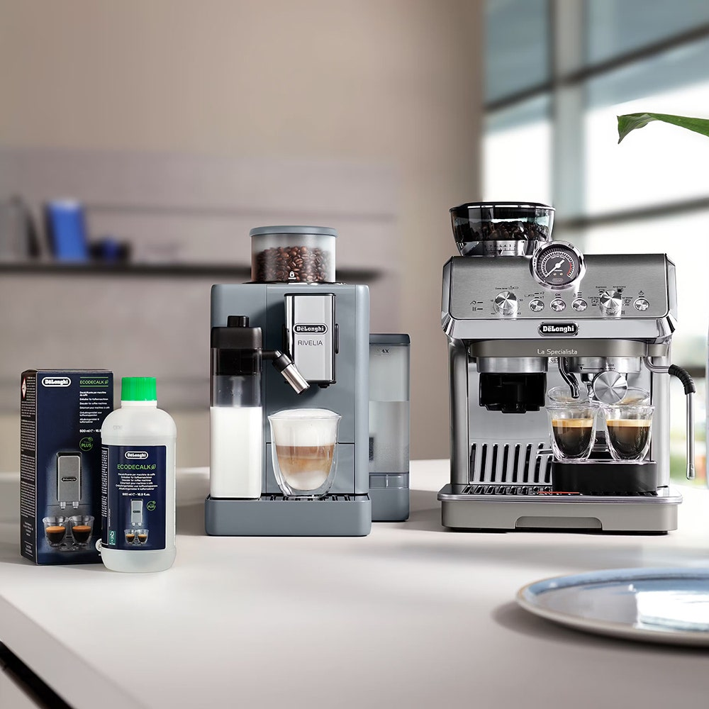 Zwei DeLonghi Espressomaschinen stehen auf einer Arbeitsplatte, eine mit Milch, die andere mit zwei Espressos.
