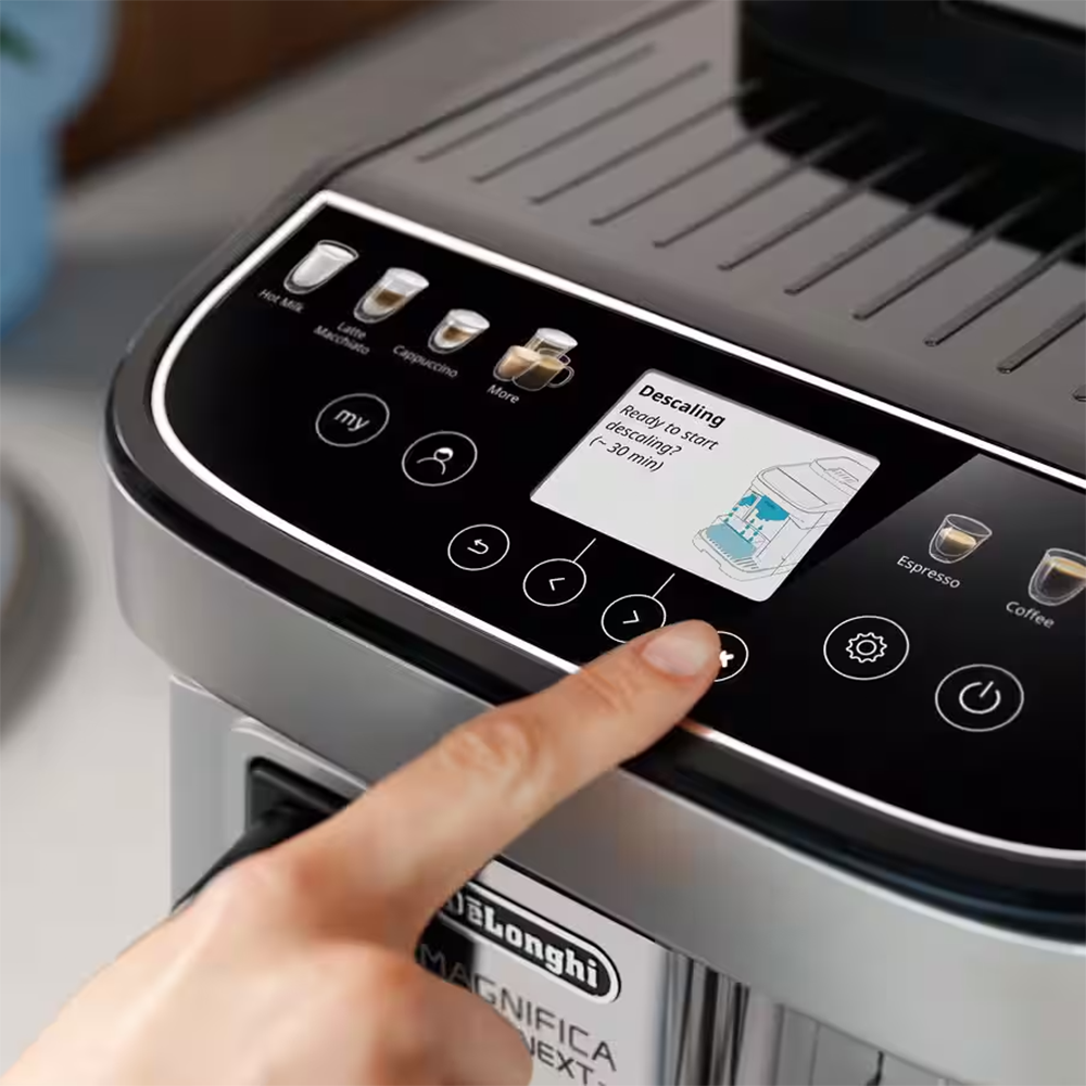 Eine Hand drückt einen Knopf auf einer Kaffeemaschine mit einem Bildschirm, der das Entkalken anzeigt.