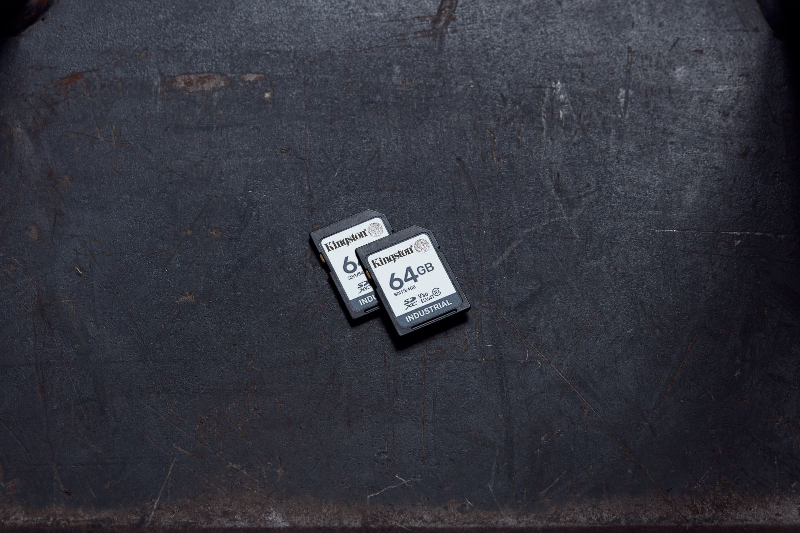 Zwei Kingston SD-Karten, 64 GB, auf dunklem, strukturiertem Untergrund.