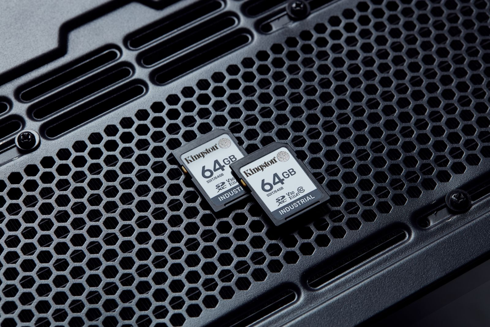 Zwei Kingston 64GB SD-Karten auf einem schwarzen, wabenförmigen Gitter.