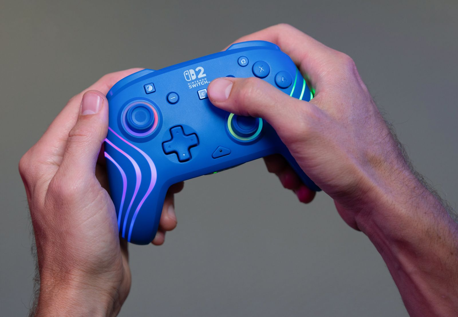 Blauer Nintendo Switch Controller mit leuchtenden Akzenten in Händen