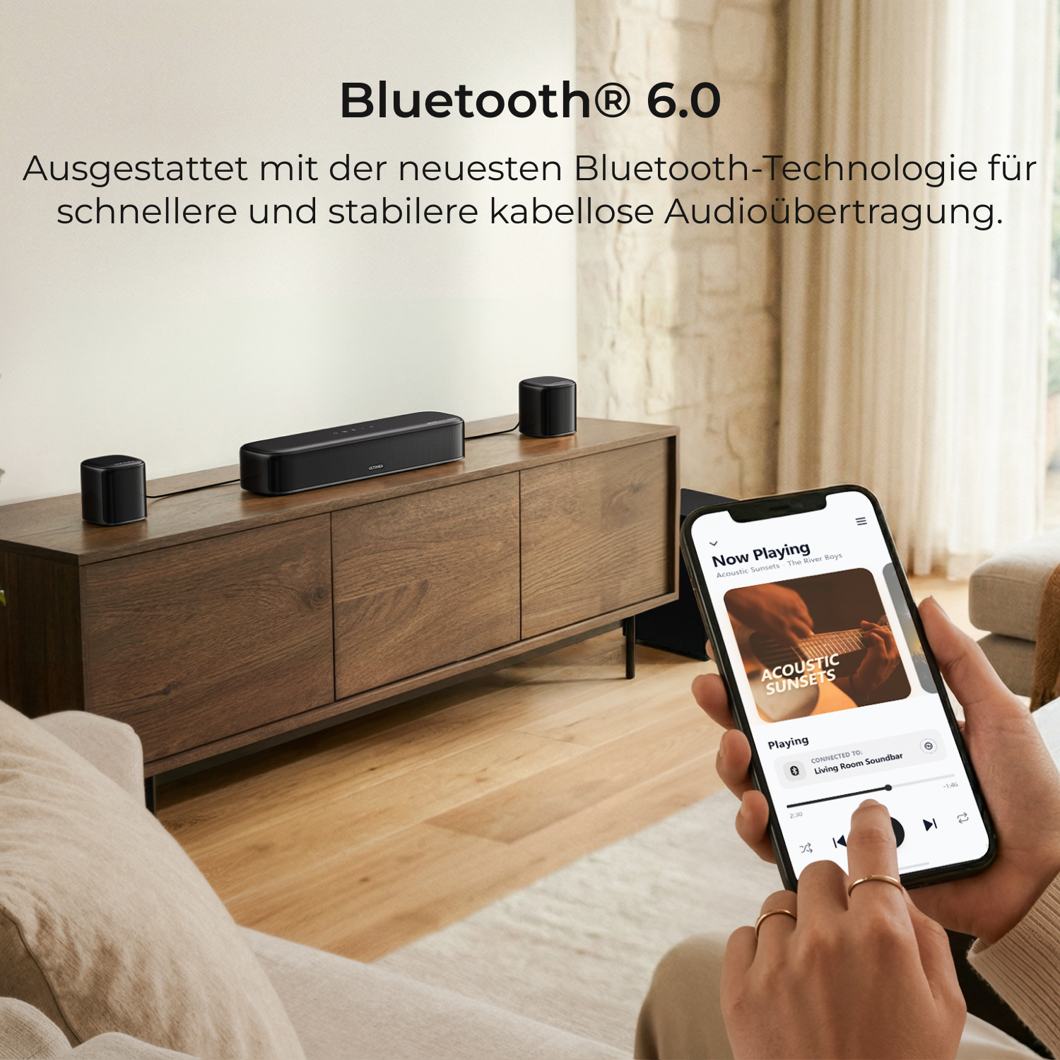 Ein Smartphone zeigt eine Musik-App. Links stehen Lautsprecher auf einem Sideboard.