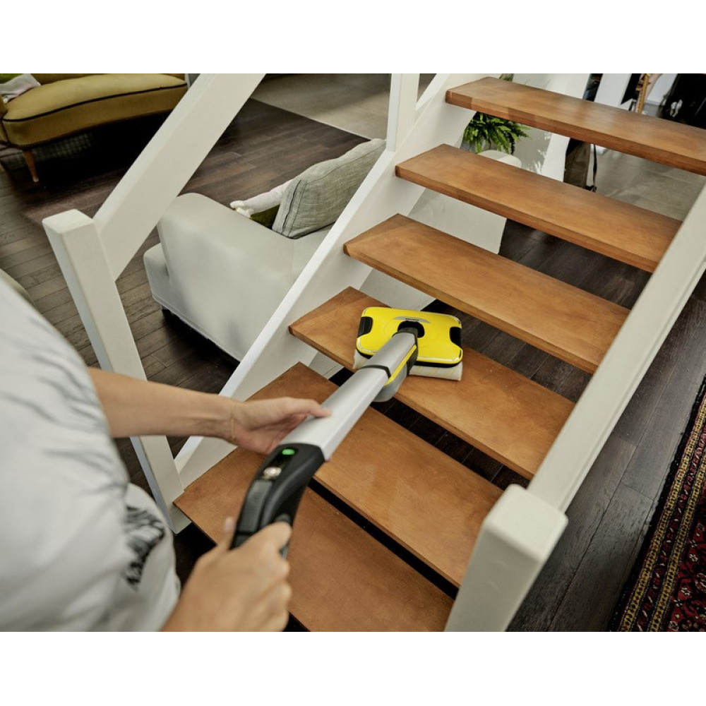 Una persona pulisce una scala in legno con un pulitore per vetri giallo.