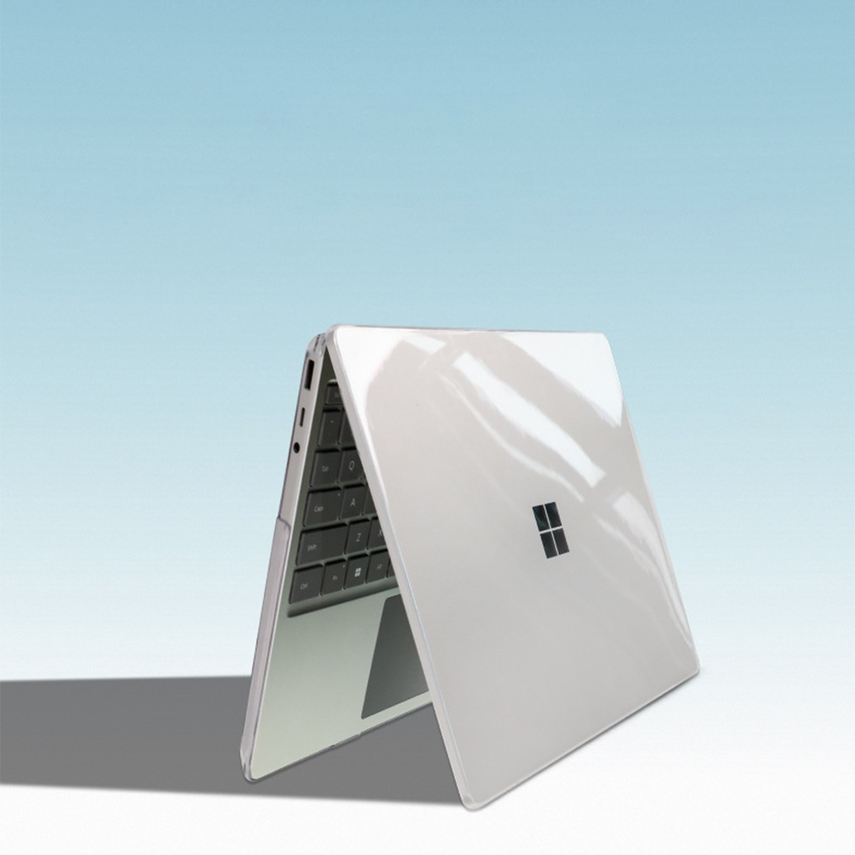 Biały laptop z otwartym ekranem, czarną klawiaturą, na niebieskim tle.