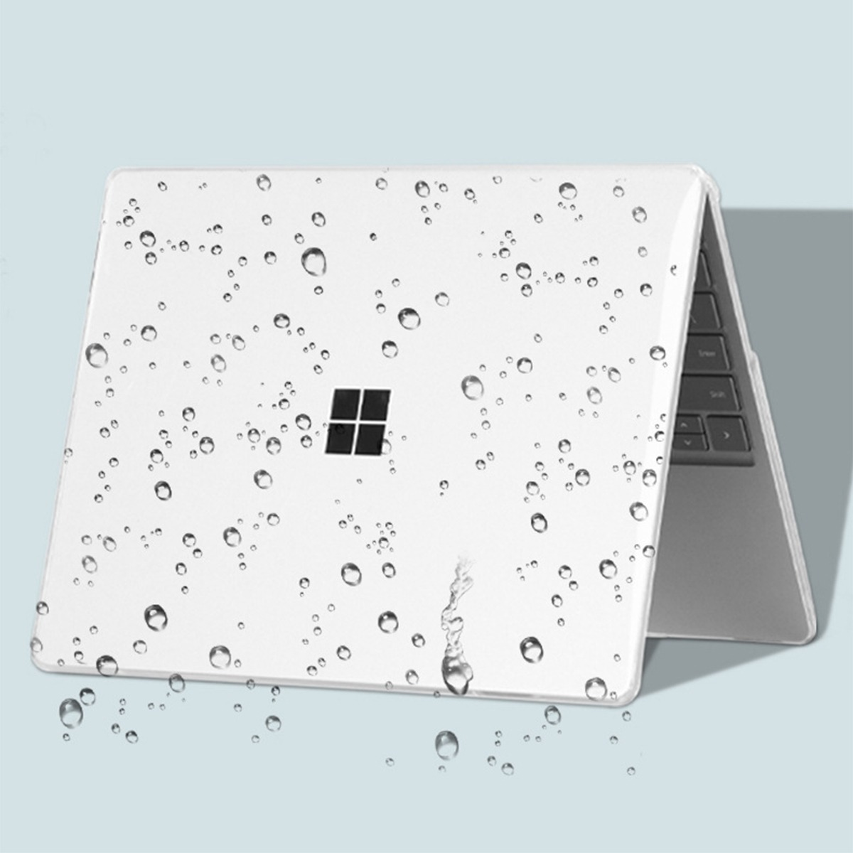 Białe etui na laptopa z kroplami wody i logo Microsoft.
