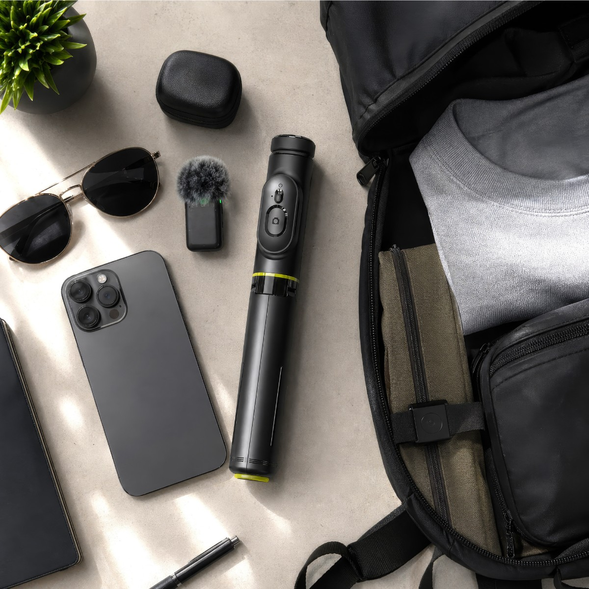 Smartfon, okulary przeciwsłoneczne, mikrofon, gimbal i plecak z ubraniami.