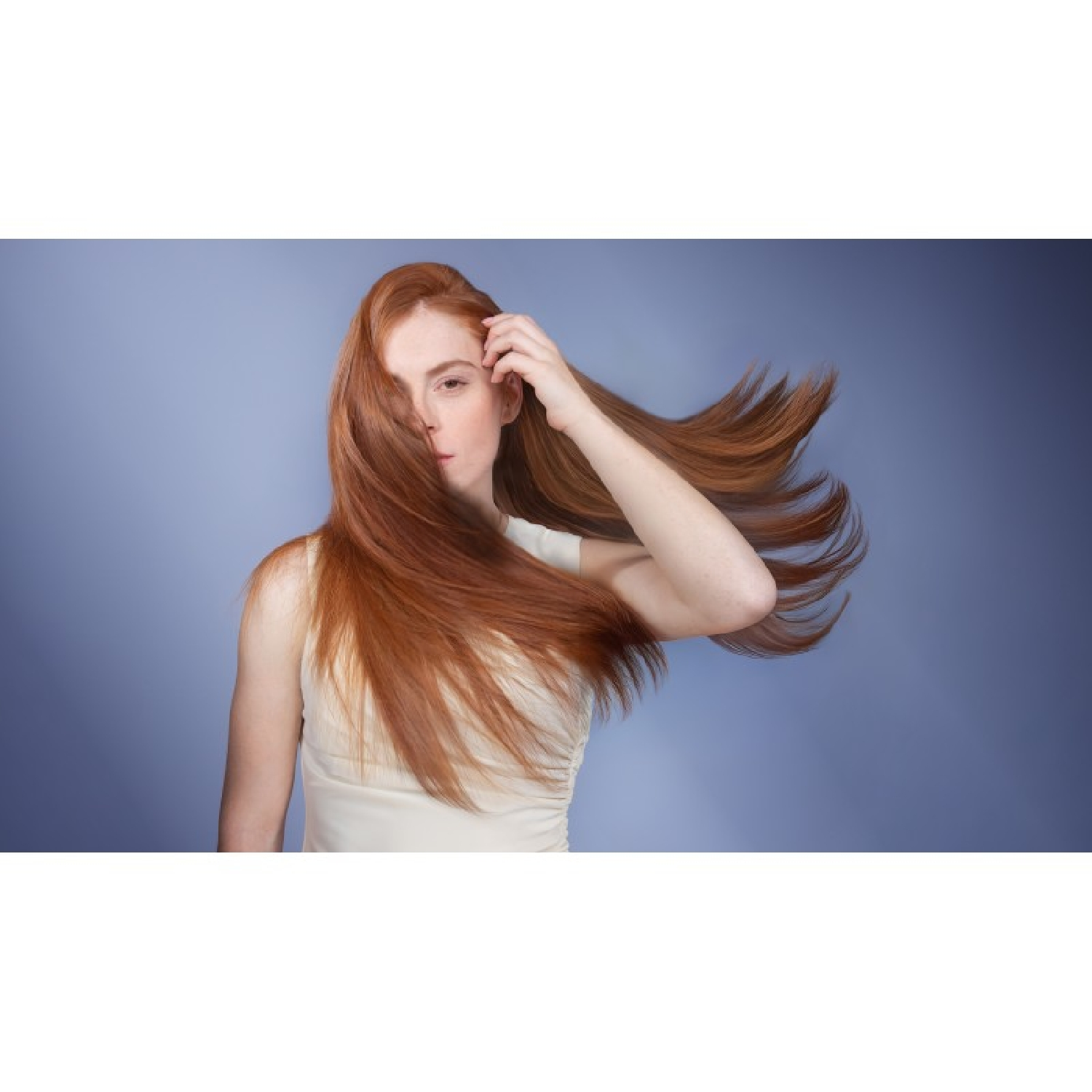 Mujer con cabello rojo largo que se mueve con el viento, viste un top color crema.