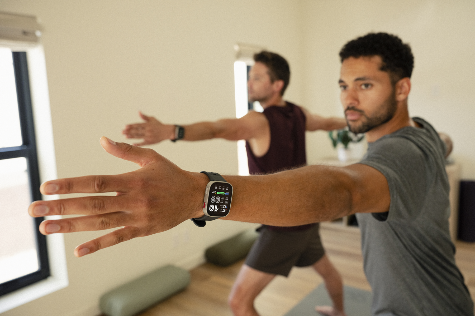 Zwei Männer in einem Raum, die Yoga machen und ihre Arme ausstrecken.