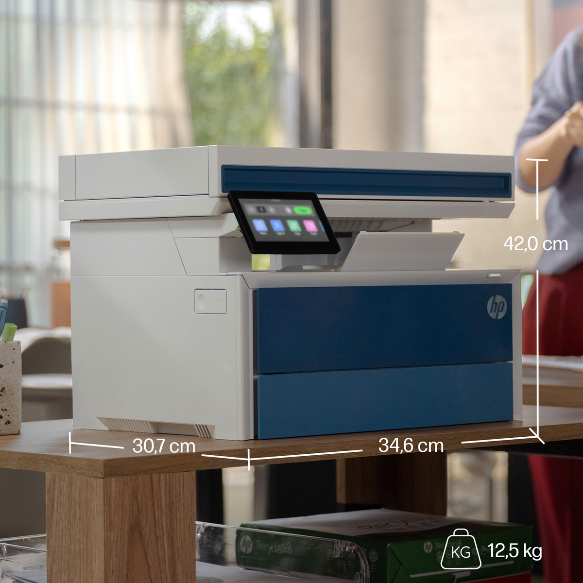 Una stampante HP bianca e blu con touchscreen su una scrivania di legno.