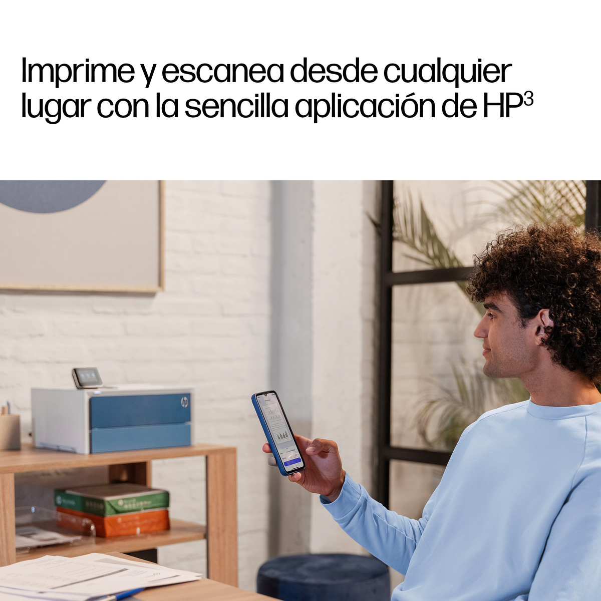 Uomo tiene telefono davanti a stampante su scaffale. Grafica sullo schermo.