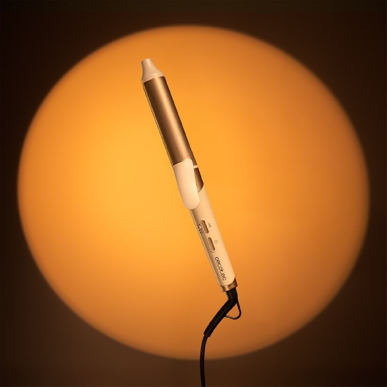 Un rizador blanco y dorado con cable negro ante un círculo naranja.