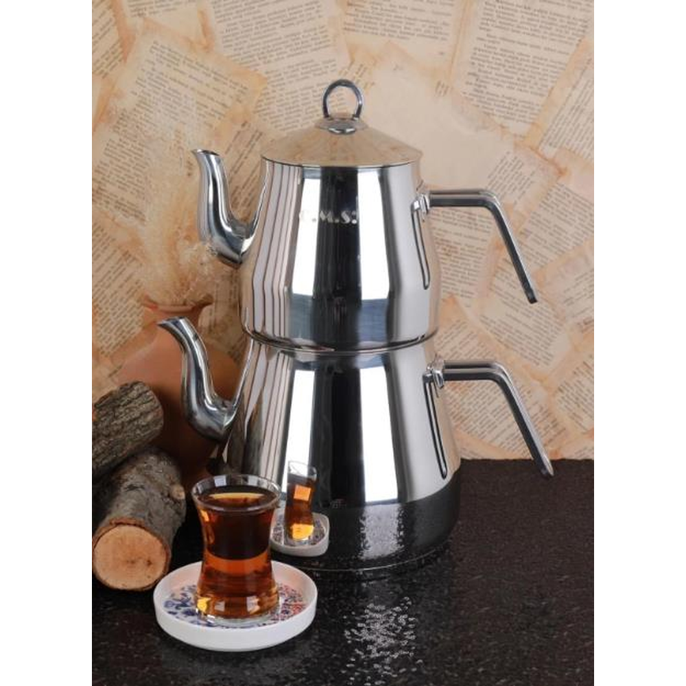 Gümüş renkli, iki katlı çaydanlık, çay bardakları ve kütüklerin yanında.