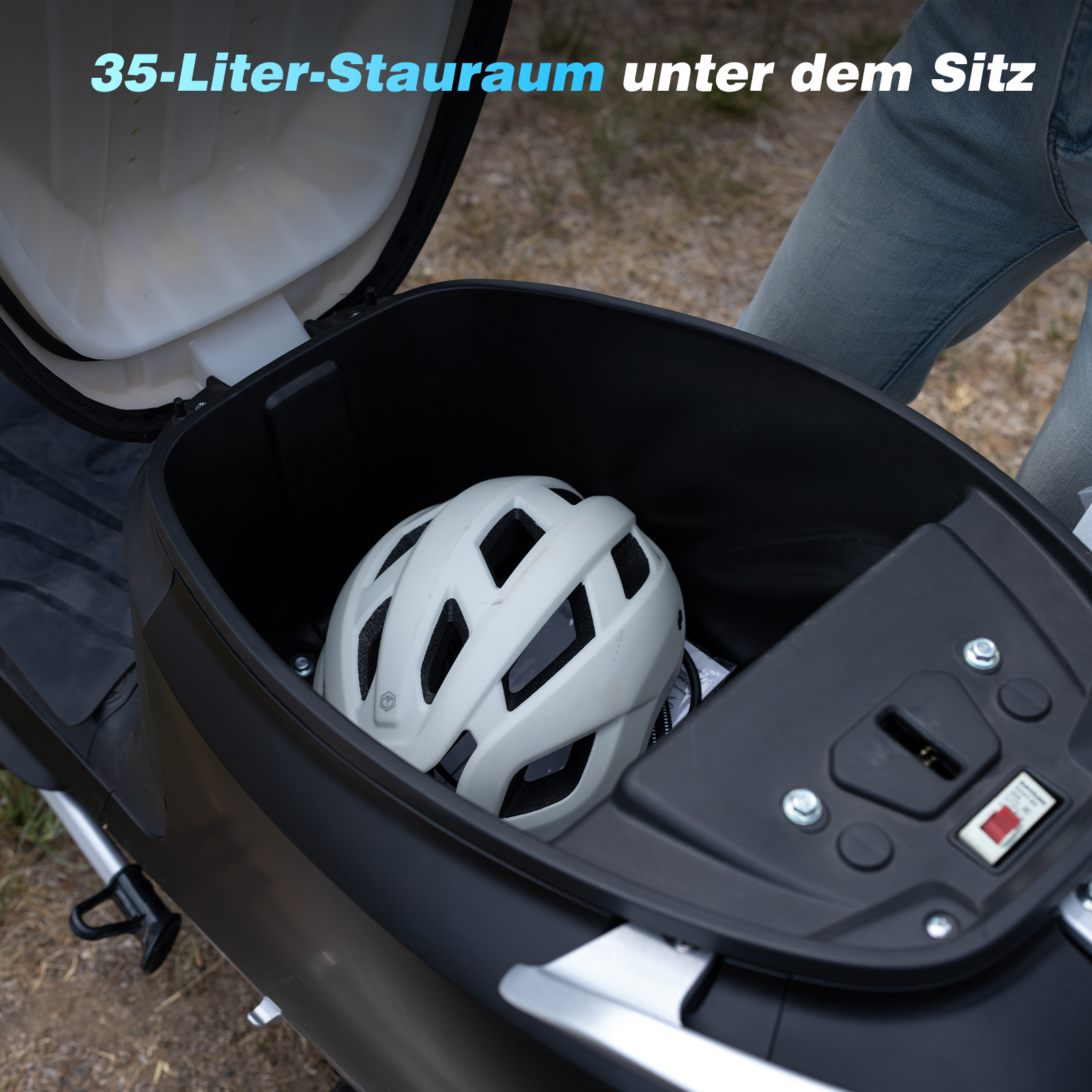Ein weißer Helm liegt in einem schwarzen Staufach eines Rollers.