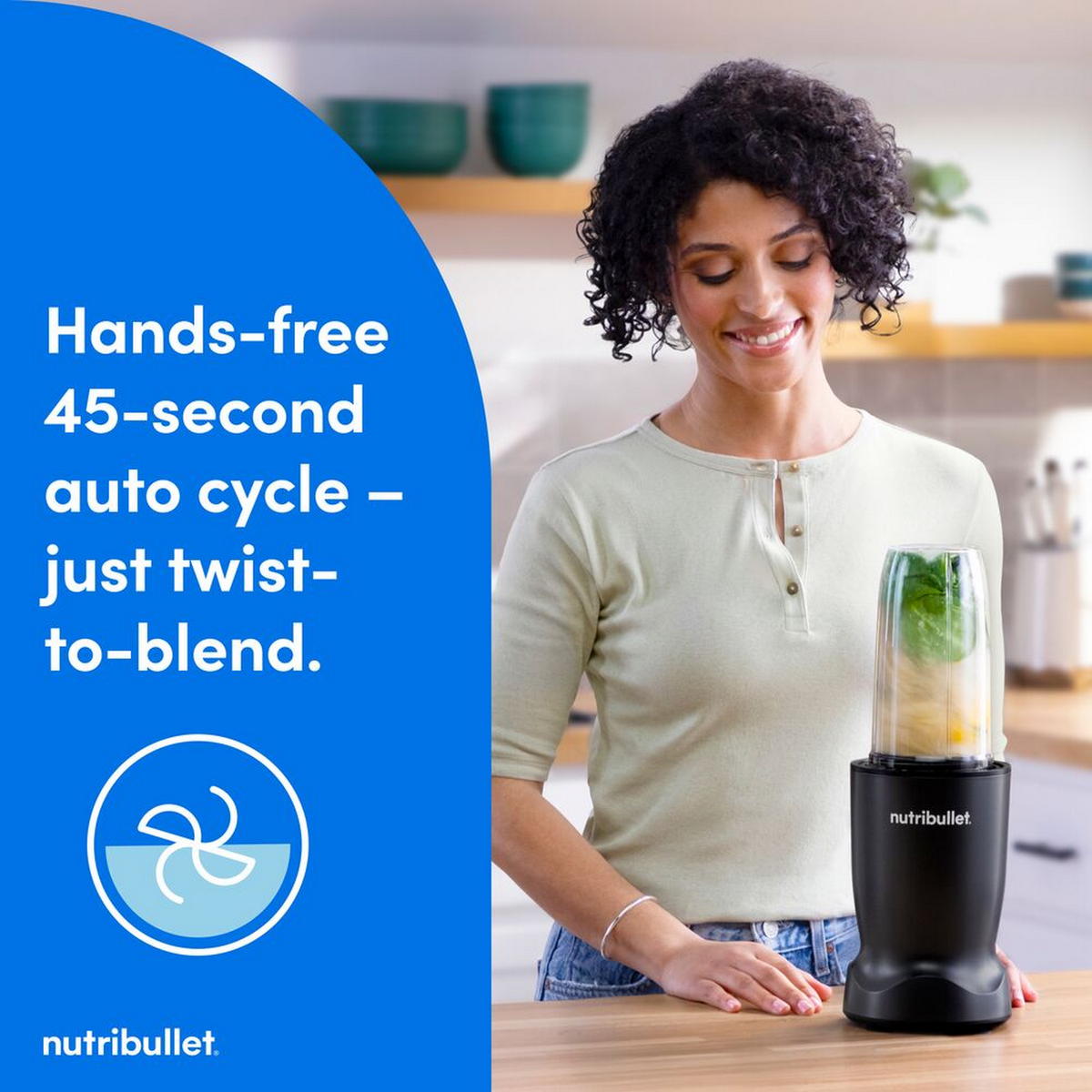 Frau lächelt und schaut auf einen Nutribullet-Mixer mit Zutaten im Becher.