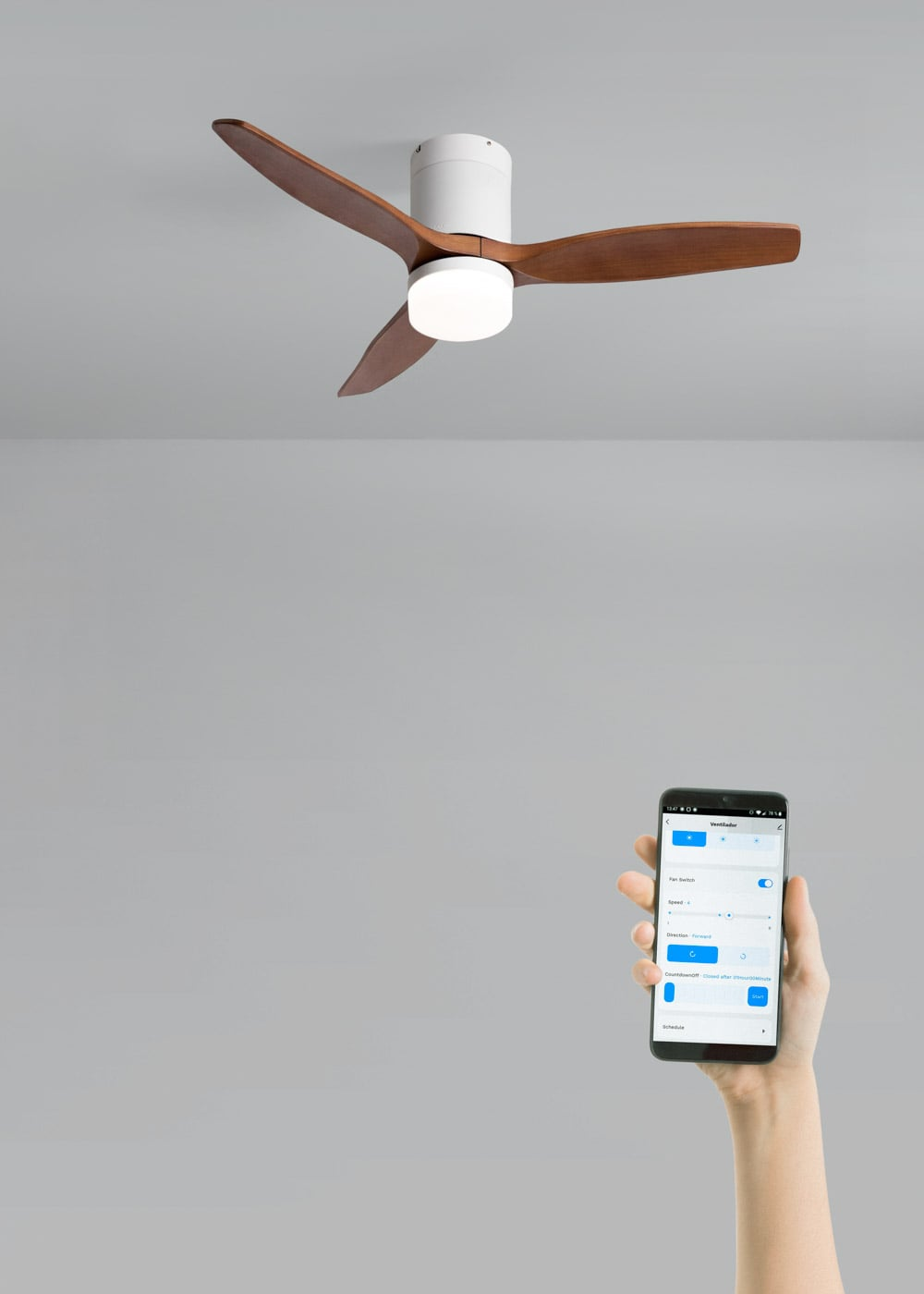 Una mano sostiene un smartphone con una app de control de ventilador; un ventilador de techo con luz al fondo.
