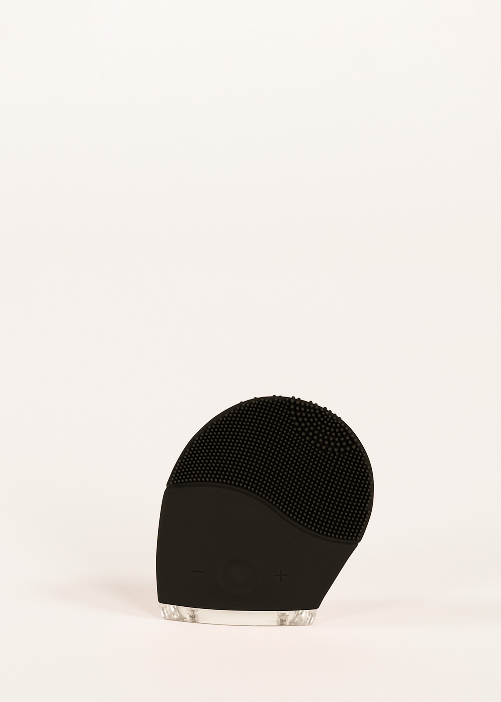 Dispositivo de cuidado de la piel negro con cerdas de silicona y base transparente.