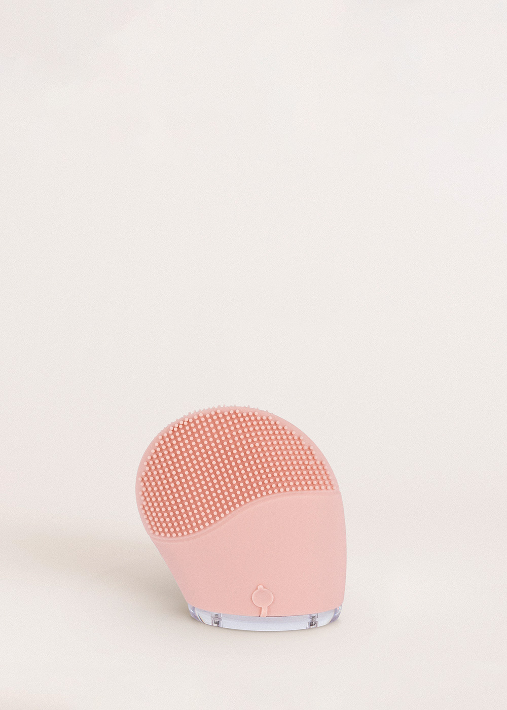 Un cepillo limpiador facial de silicona rosa con cerdas finas y base transparente.