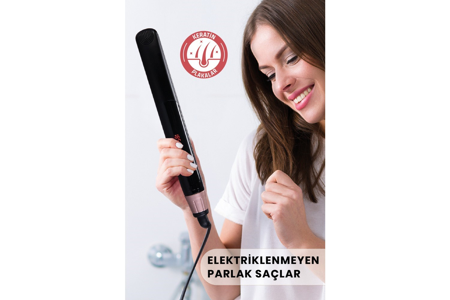 Kadın, parlak saçları gösteren keratin logolu siyah düzleştirici tutuyor.