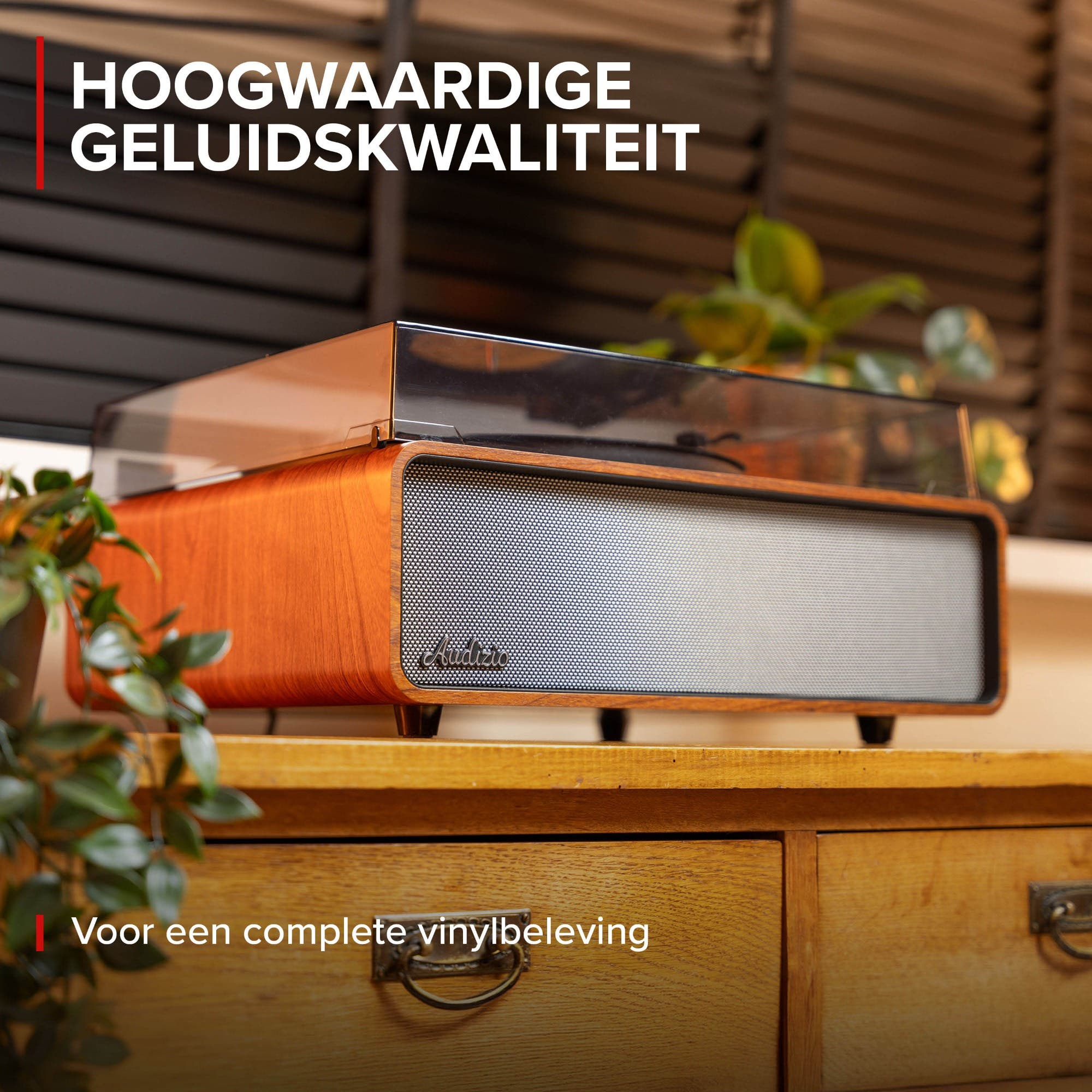 Un tocadiscos de madera con altavoz plateado se asienta sobre un mueble de madera.