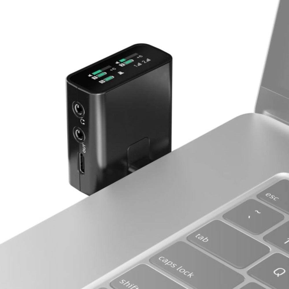 Czarny interfejs audio leży na srebrnym laptopie. Interfejs ma porty i mały ekran.