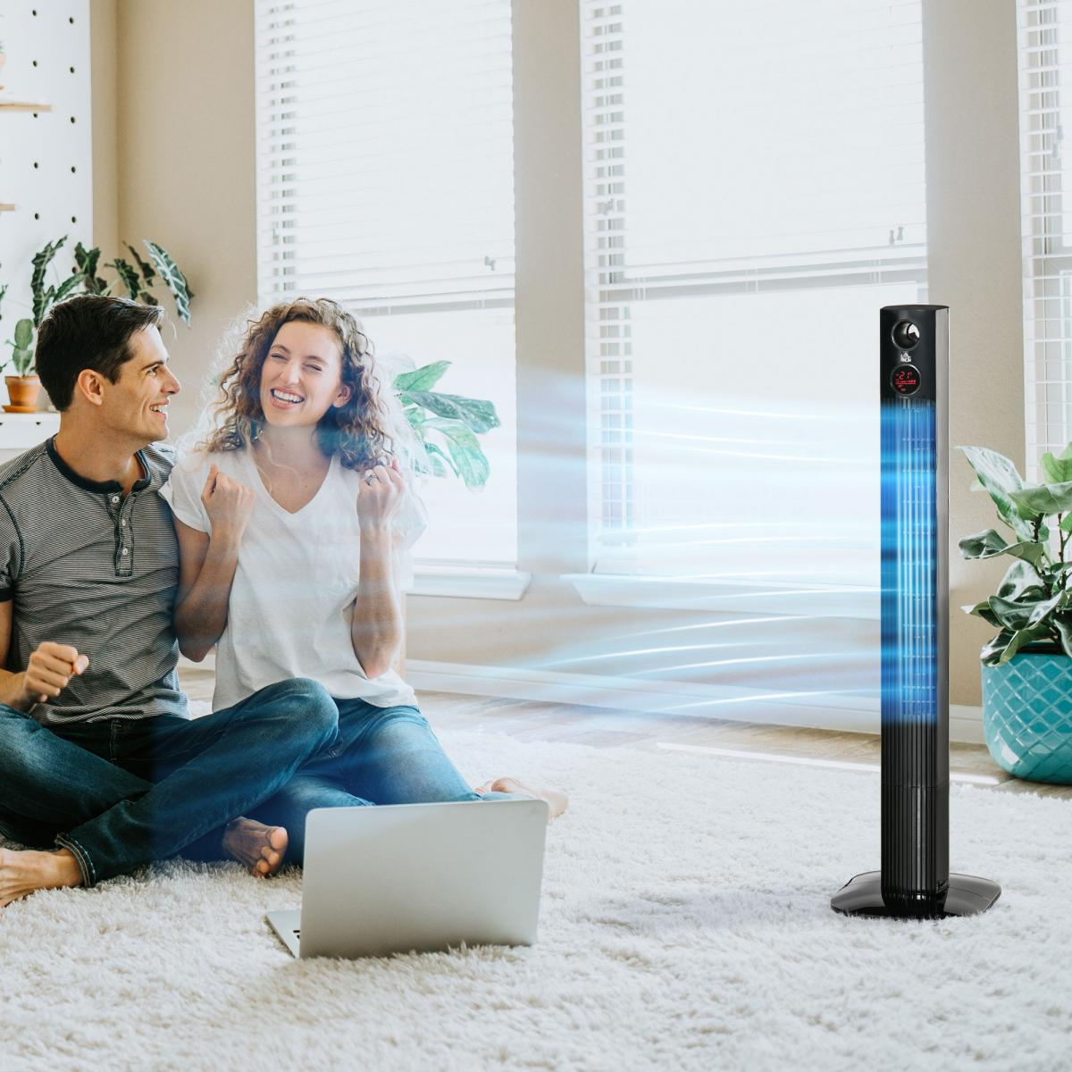 Paar jubelt beim Laptop gucken, während Ventilator den Raum kühlt