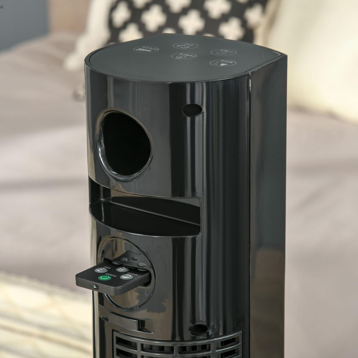 Ein schwarzer Turmventilator mit Fernbedienung, die in einen Schlitz gesteckt ist.