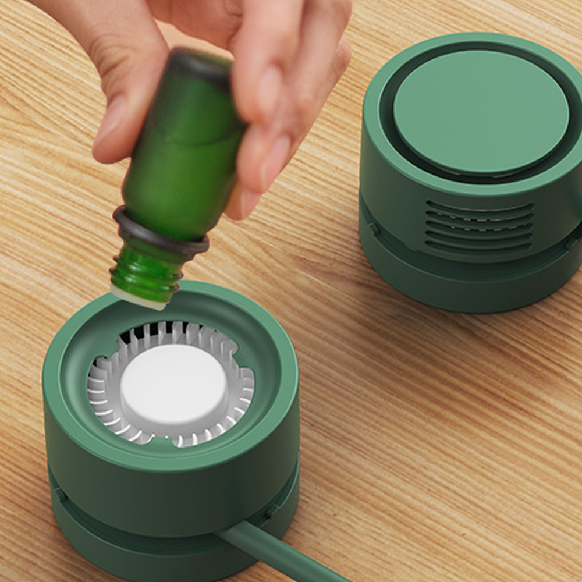 Grüne Flasche wird in einen grünen Diffusor auf einem Holztisch gestellt.